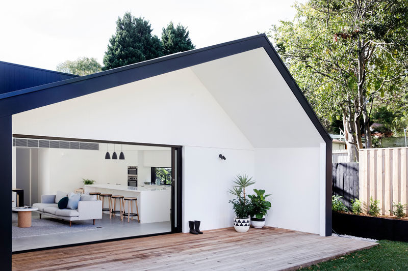 The living room of this modern house addition opens to a partially covered outdoor timber deck, that operates as an extension of the internal entertaining spaces. #OutdoorSpace #Deck #ModernHouse