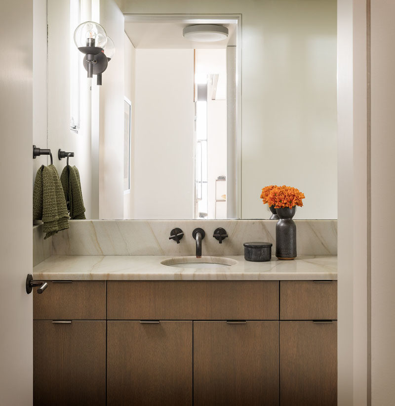 Bathroom Ideas - This modern bathroom features a wood vanity topped with a stone countertop, while a mirror takes up the rest of the wall. #BathroomIdeas #BathroomDesign