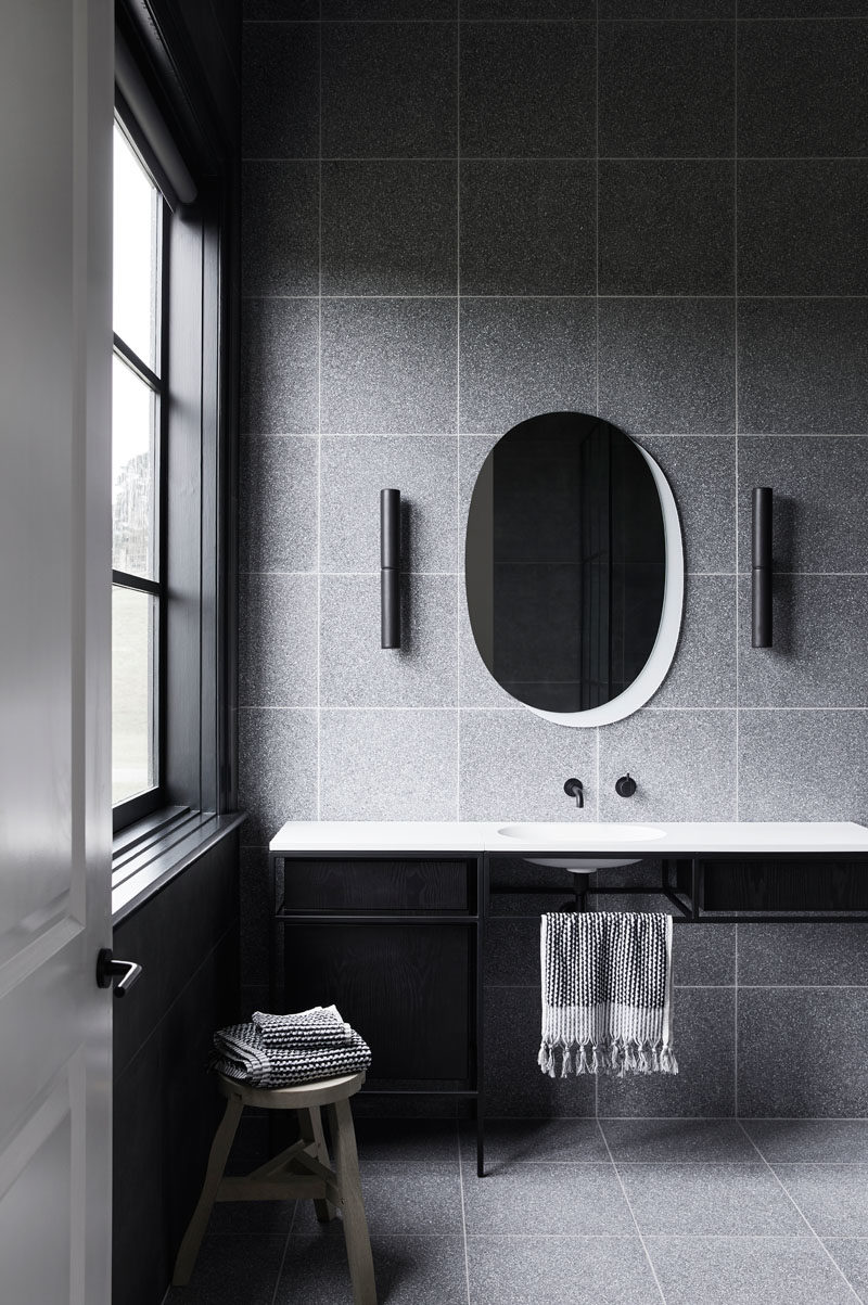 Bathroom Ideas - In this modern grey, black and white bathroom, grey tiles are combined with a black-framed vanity and a white countertop that has a built-in basin. #BathroomIdeas #BathroomDesign #ModernBathroom
