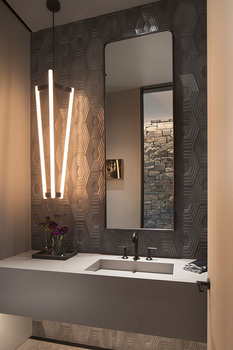 Bathroom Ideas - In this modern bathroom, grey geometric tiles cover the walls, while the tall mirror and long pendant light draw attention to the height of the room. #BathroomIdeas #ModernBathroom