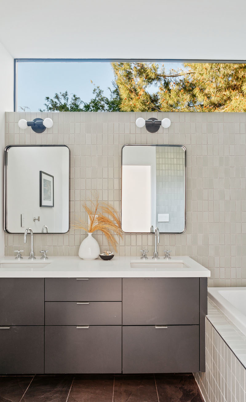 Bathroom Ideas - This modern bathroom features clerestory windows that provide a glimpse of the trees, while a bathtub has been built-in beside the vanity. #BathroomIdeas #ModernBathroom #BathroomDesign