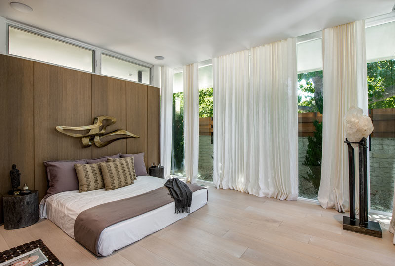 Bedroom Ideas - This modern master bedroom has a wood accent wall that acts as a headboard, while wide plank White Oak has been used for the flooring. #MasterBedroom #BedroomIdeas #BedroomDesign #ModernBedroom