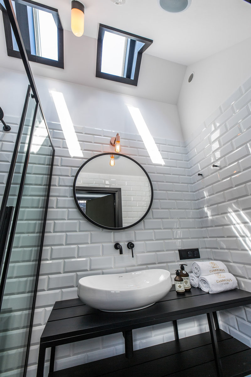 Bathroom Ideas - Black design elements are featured in this modern bathroom, with a black vanity, black flooring, and black shower frame. White tiles and skylights help to keep the room bright. #BlackBathroom #BathroomIdeas #Bathroom #ModernBathroom