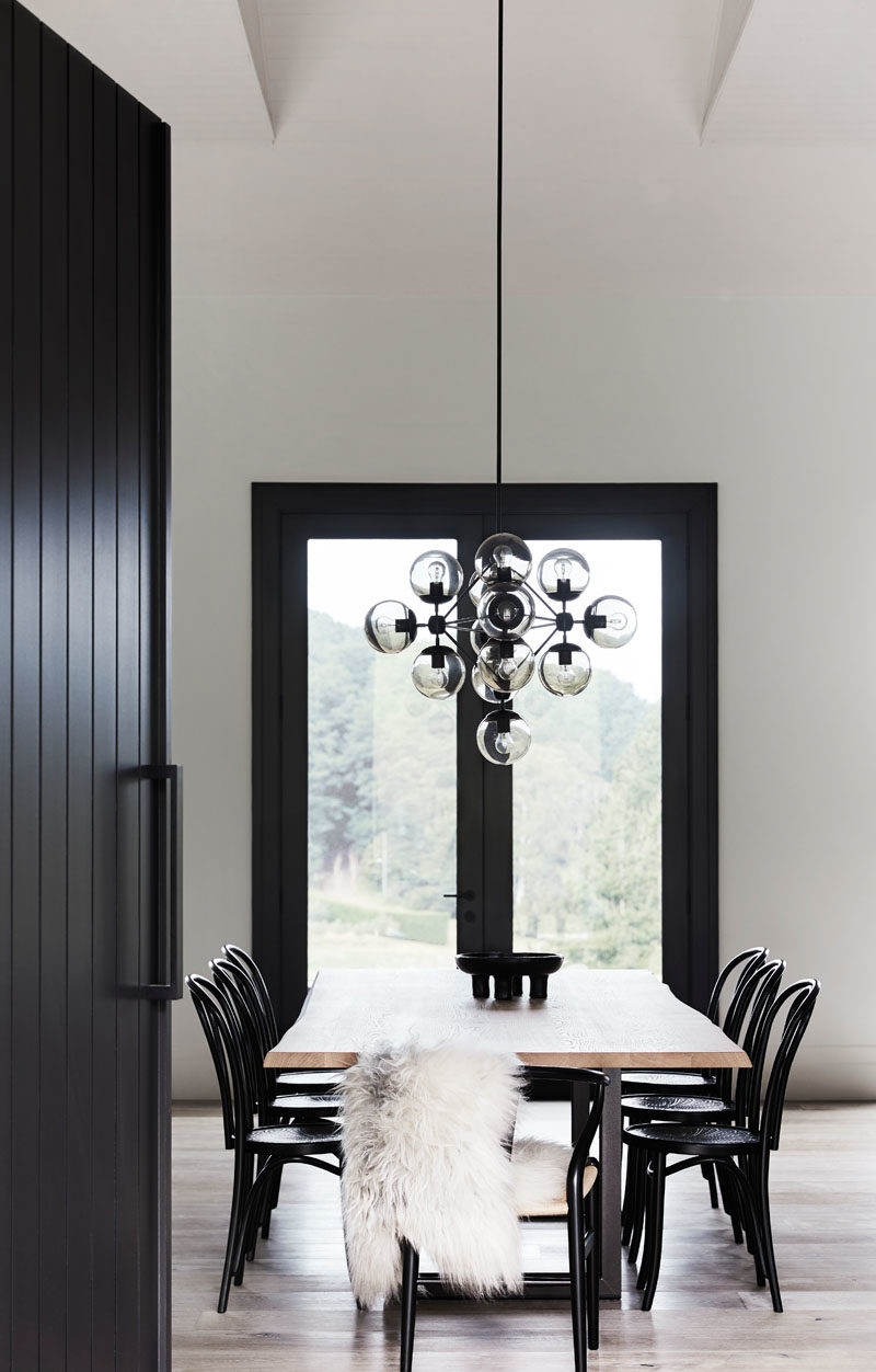 Dining Room Ideas - In this modern farmhouse, a large wood dining table surrounded by black chairs, is positioned beneath a sculptural chandelier. #DiningRoomIdeas #ModernDiningRoom