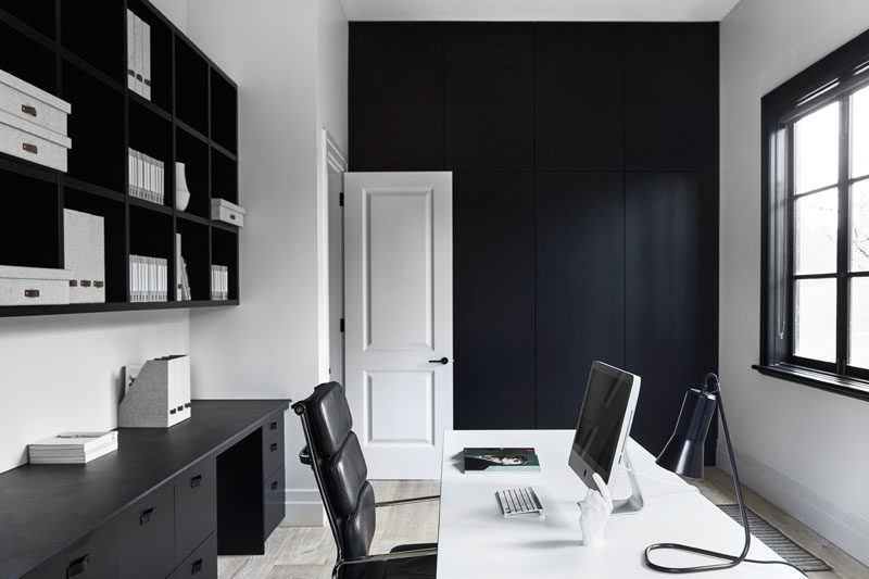 Home Office Ideas - In this modern home office, a black accent wall complements the black shelving and window frames. #ModernHomeOffice #HomeOfficeIdeas #BlackAccentWall