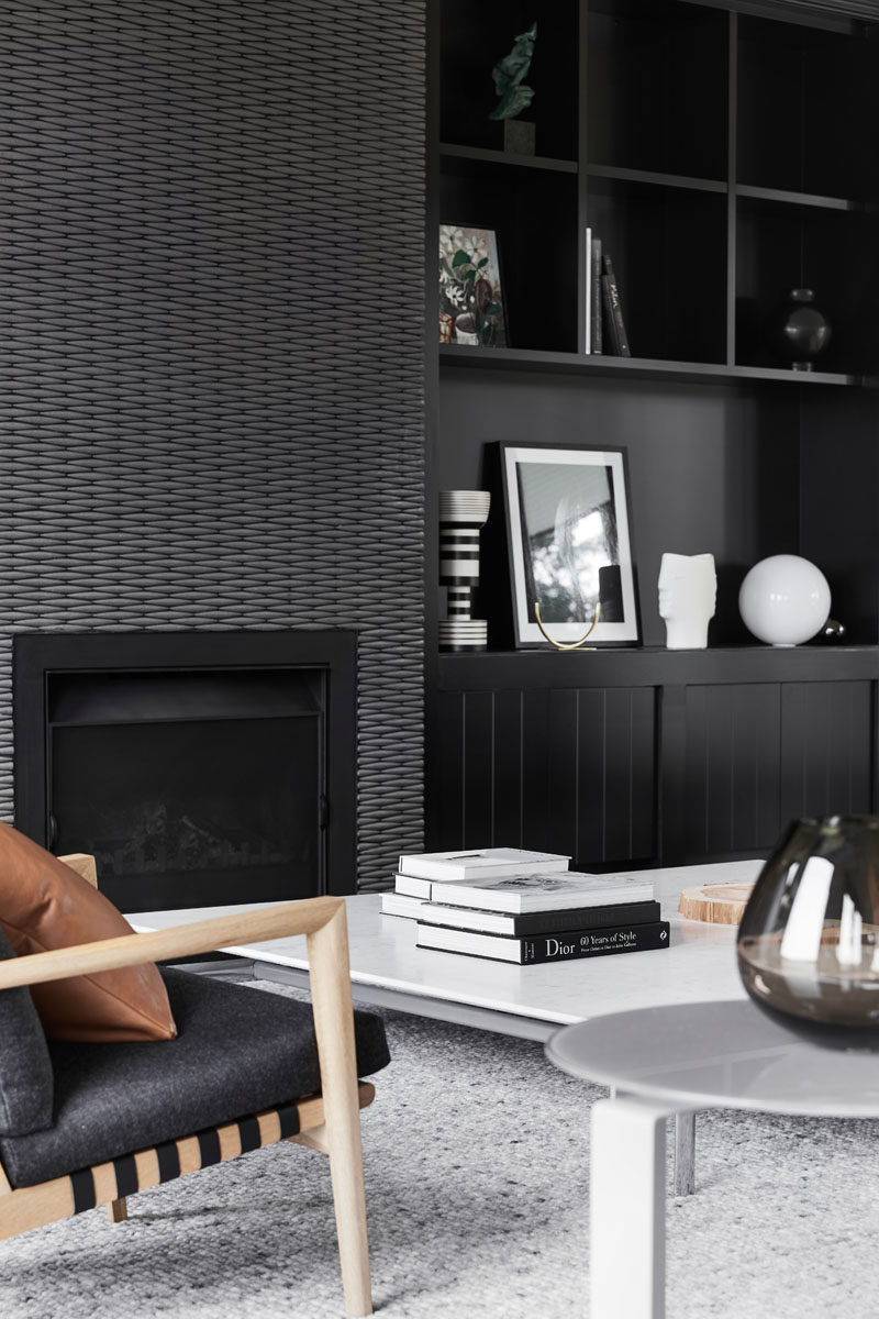 Shelving Ideas - Custom-designed shelving has been added on either side of the fireplace, providing dedicated areas for displaying decorative elements. #BlackShelving #Fireplace #ModernLivingRoom