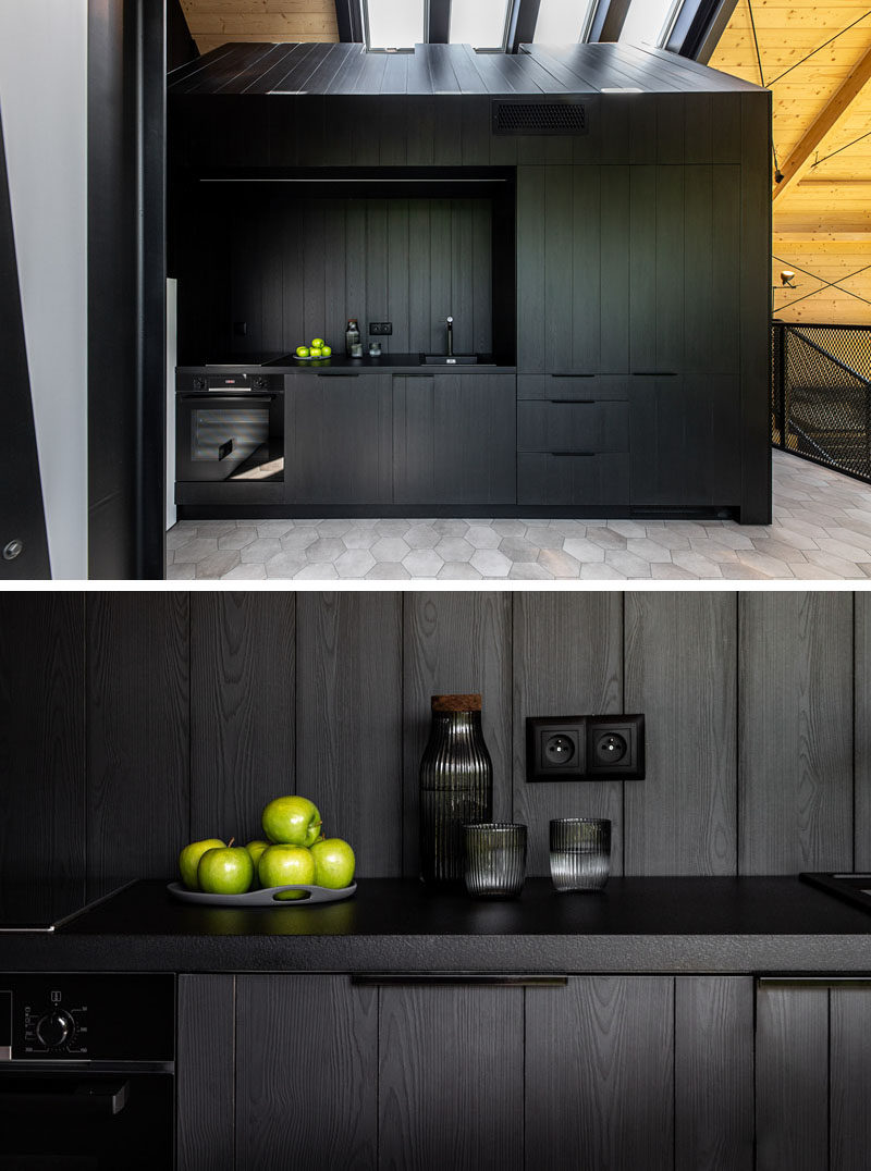 Kitchen Ideas - In this modern black kitchen, black cabinets complement the black dining furniture, the black structural elements, and the black window frames. #BlackKitchen #KitchenIdeas #ModernKitchen #KitchenDesign