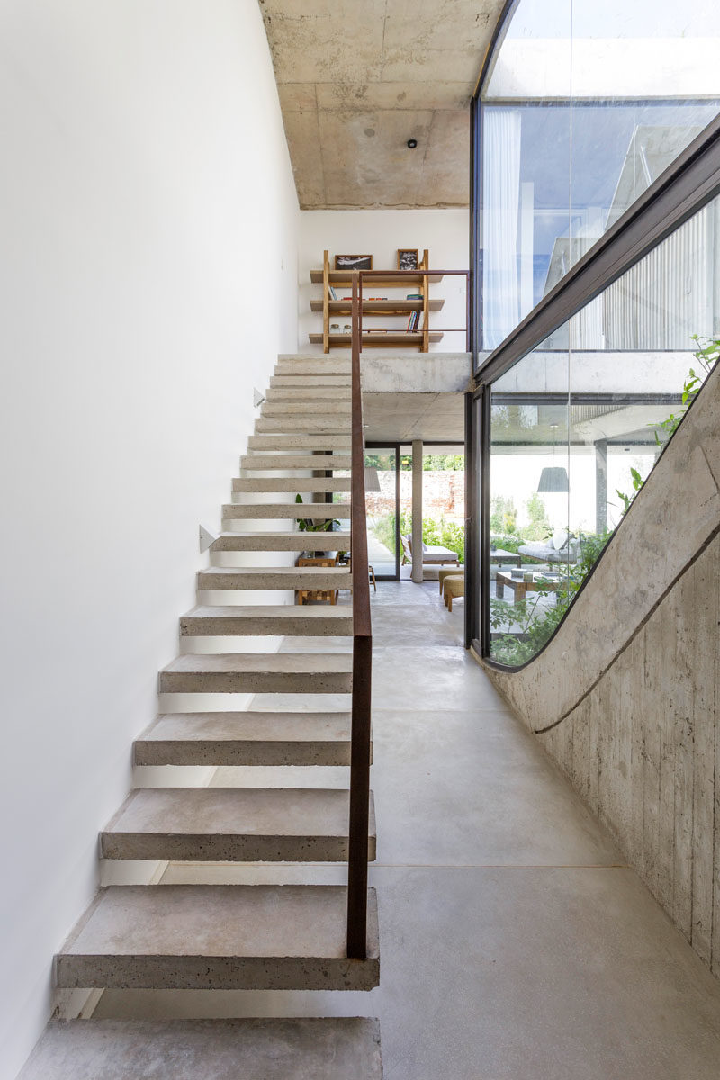 Stair Ideas - Concrete stairs with a steel handrail lead to the upper level of this modern house, where the bedrooms and bathrooms are located. #ConcreteStairs #StairIdeas #ModernStairs