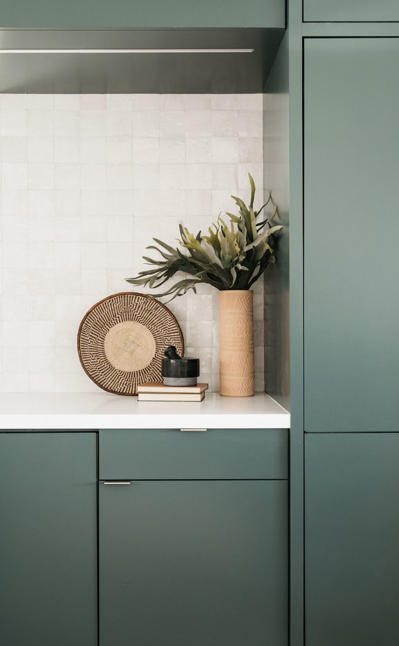 Kitchen Ideas - this modern kitchen features minimalist deep green cabinets paired with a light backsplash and countertop. #ModernKitchen #GreenKitchen #KitchenIdeas