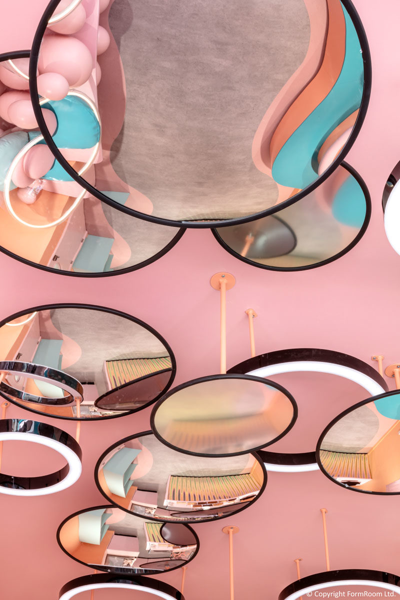 This eye-catching ceiling installation combines suspended concave and convex iridescent mirrors, representing bubbles from this dessert bar's core product offering. #CeilingInstallation #MirroredCeiling #CafeDesign #InteriorDesign