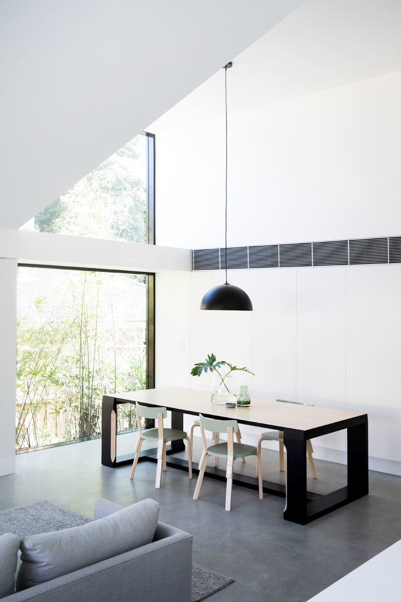 Dining Room Ideas - This modern dining room is positioned next to two large picture windows that frame the trees and let an abundance of natural light into the home. #DiningRoom #Windows #ModernInterior