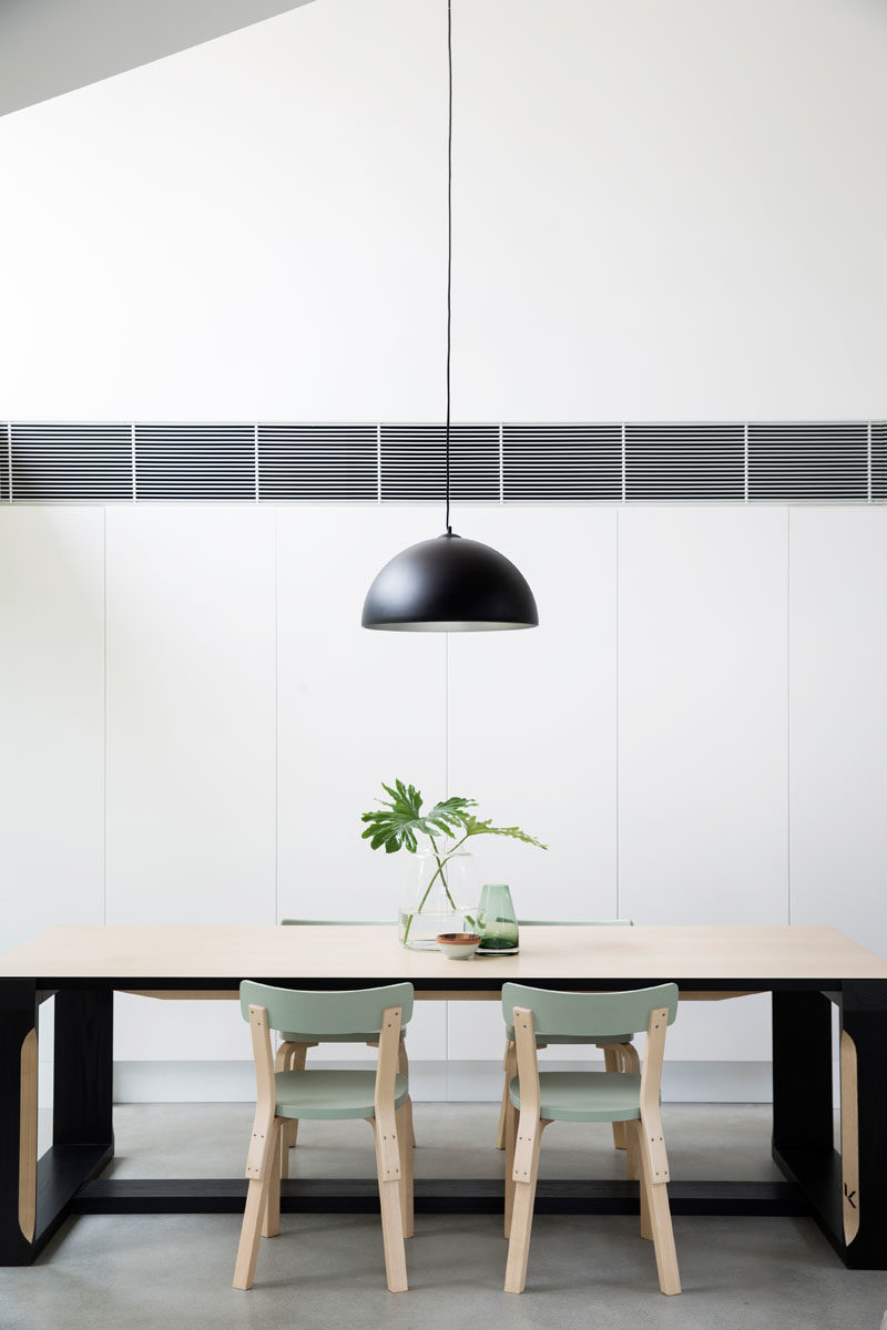 Dining Room Ideas - This modern dining room is positioned next to two large picture windows that frame the trees and let an abundance of natural light into the home. #DiningRoom #Windows #ModernInterior