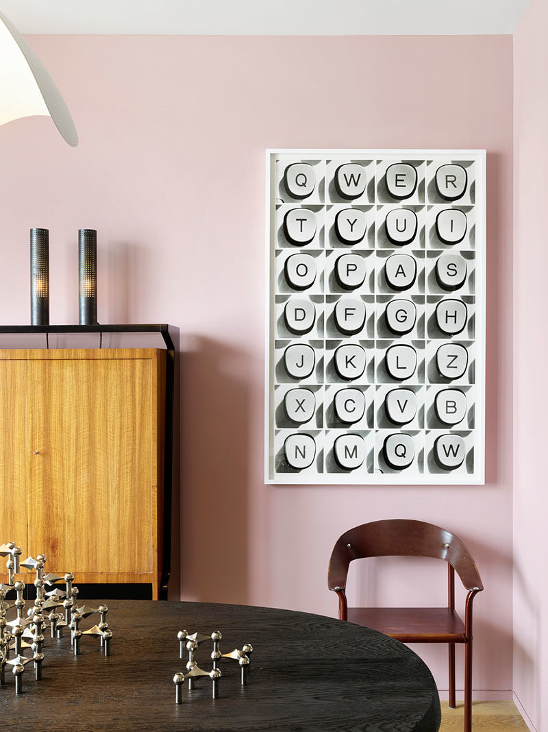 Dining Room Ideas - In this modern dining room, soft pink has been used to create a colorful backdrop for the artwork and dining table, which was designed by Jamie Bush + Co., and is shaped like an oblong pebble with a highly textured wire-brushed finish, that exposes the grain of the blackened oak. #DiningRoomIdeas #DiningRoom #PinkRoom #PinkWalls #InteriorDesign