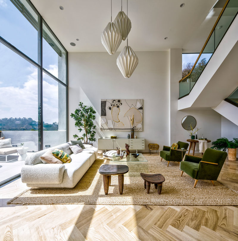 Living Room Ideas - This modern living room has floor-to-ceiling windows that provide a view of the neighborhood. #HighCeilings #LivingRoomIdeas #WindowIdeas