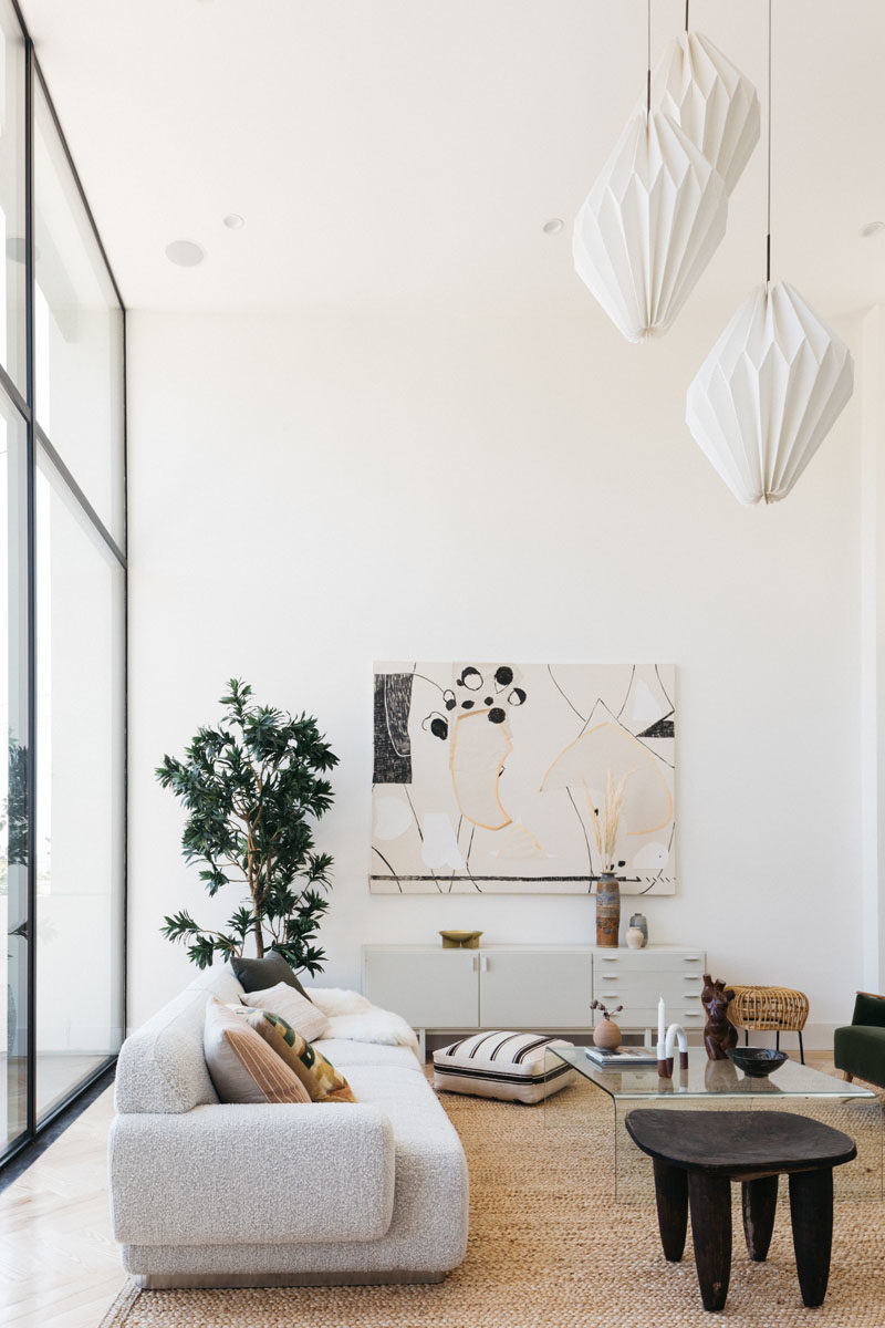 Living Room Ideas - This modern living room has floor-to-ceiling windows that provide a view of the neighborhood. #HighCeilings #LivingRoomIdeas #WindowIdeas