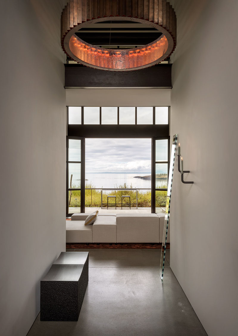 Hallway Ideas - In this modern hallway, featured pieces are on show, like John Eric Byers’ iconic block bench in blackened maple, and a “Seeing Glass” art mirror piece by Sabine Marcelis. #HallwayIdeas #ModernHallway