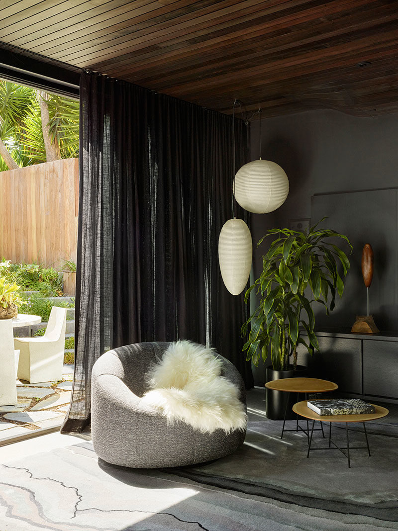 Living Room Ideas - This dark lounge has bold artwork and a vintage Danish sculptural floor lamp from the 1960's. #LivingRoomIdeas #BlackWalls #LivingRoom