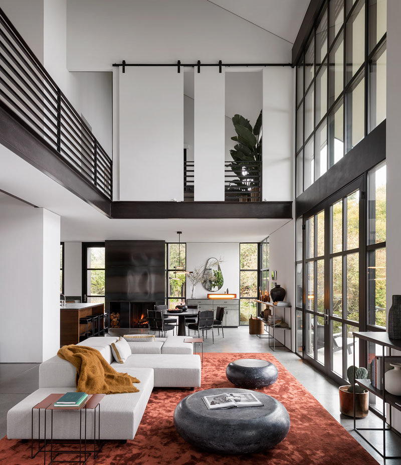 Living Room Ideas - Double height windows in this modern living room frame the picturesque bay and illuminate the silk Tai Ping rust carpet, while open shelving credenzas were designed to align with the window mullions. #LivingRoomIdeas #InteriorDesign #LivingRoom #ModernInterior