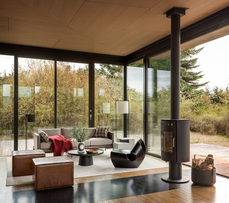 This modern guest cabin is furnished with Made in Ratio’s sculptural Cowrie Chair, a TRNK Truss Sofa and sculptural side table, and the Rodan Coffee Table by Pinch. #InteriorDesign #GlassWalls #CabinDesign