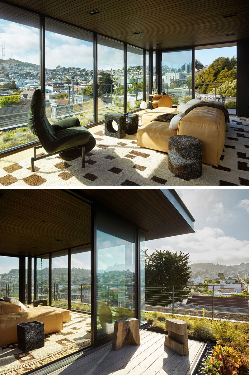 This modern rooftop lounge with its glass walls, is furnished with a graphic rug, a plush couch, and eucalyptus stools by Ido Yoshimoto. #LivingRoom #GlassWalls