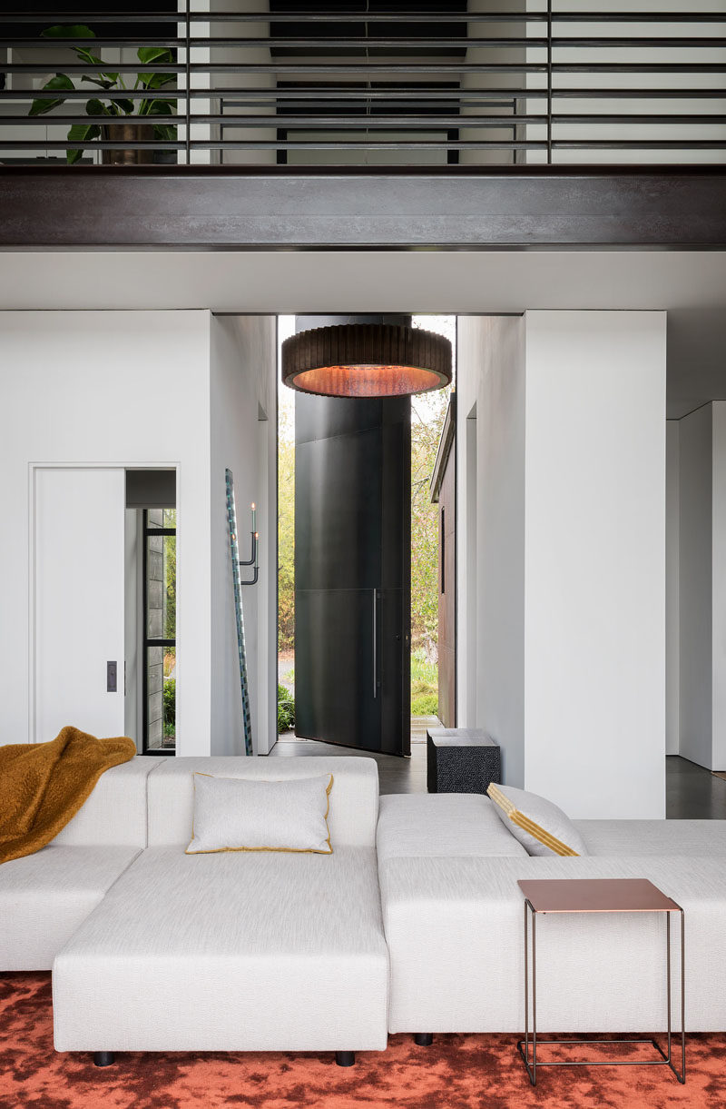 Hallway Ideas - In this modern hallway, featured pieces are on show, like John Eric Byers’ iconic block bench in blackened maple, and a “Seeing Glass” art mirror piece by Sabine Marcelis. #HallwayIdeas #ModernHallway