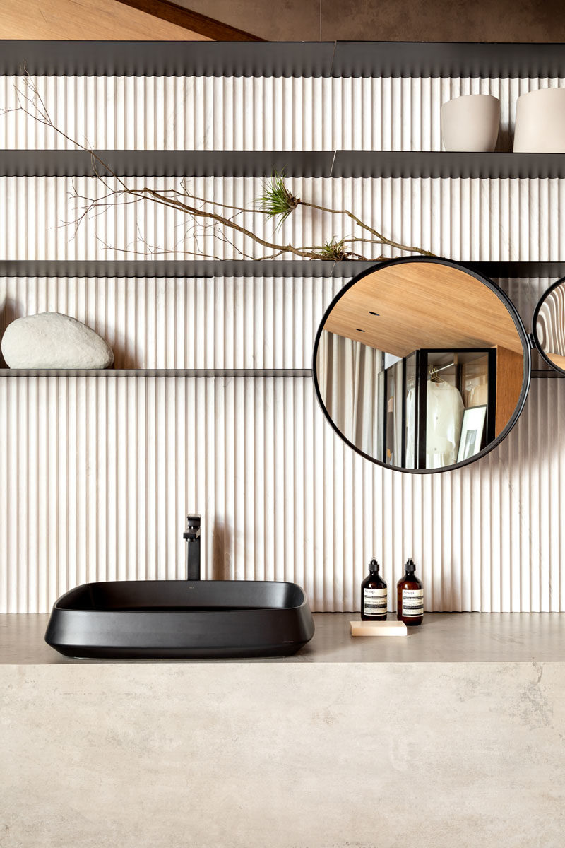 Bathroom Ideas - In this modern bathroom, that also shares the room with the bedroom, a marble bathtub is positioned by the bed with plants providing some privacy, while textured stone has been used for the backsplash and the vanity. #BathroomIdeas #BathroomDesign #Bathroom