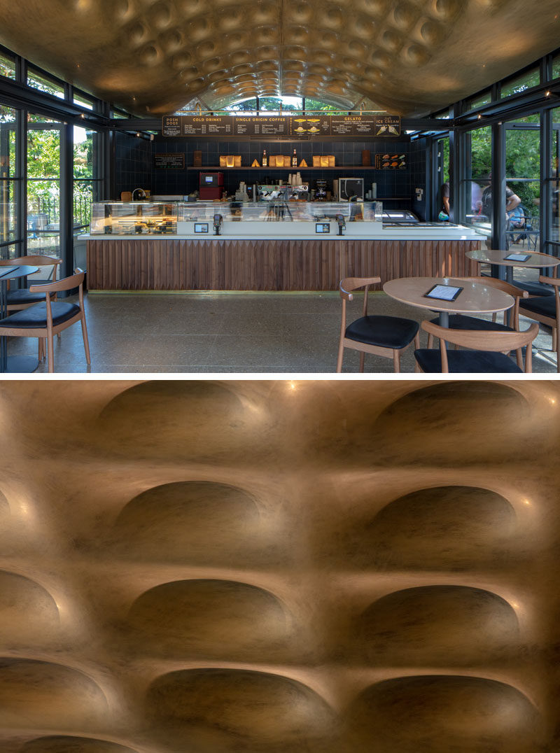 The undulating canopy of this modern coffee house, designed to respond to the movement of the nearby lake, has been hand-painted using specialist techniques to give an aged-brass finish, and is intricately textured on the underside with snakeskin-inspired, coffer-like dimples. #Ceiling #AccentCeiling #Architecture #ModernArchitecture #Design