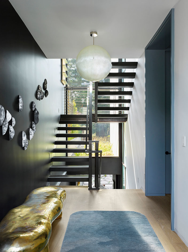 Inside this modern house, there's a clear view from the foyer of the rear garden and the stairs that connect the various levels of the home. #InteriorDesign #Stairs #StairIdeas