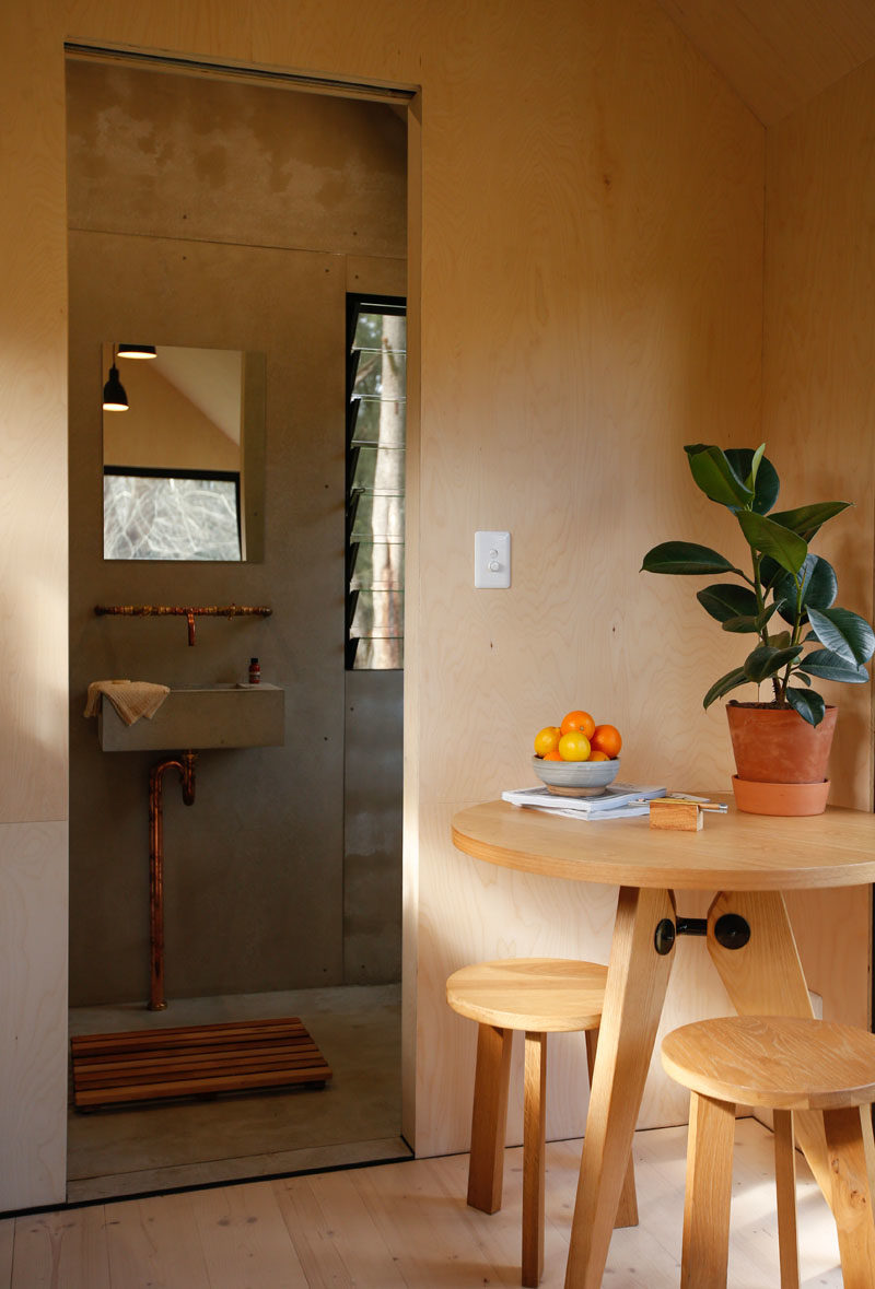 A sliding door in this tiny house opens to reveal the bathroom, where there's a composting toilet, vanity area, and a shower. #TinyHouse #TinyHome #Bathroom