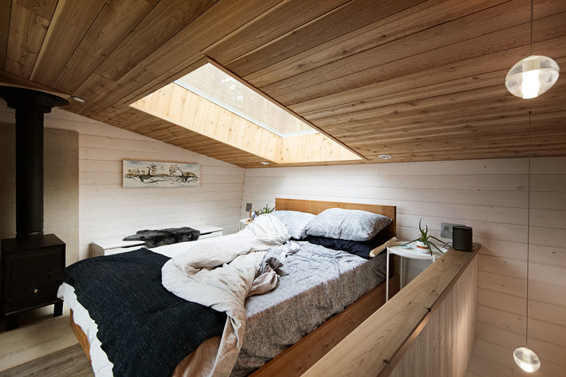 Tiny House Ideas - This modern tiny house has stairs that lead up to the lofted bedroom, that's kept bright by the use of a skylight. When it's cool outside, there's a black wood burning stove to keep the space warm. #LoftBedroom #TinyHouse #BedroomIdeas #WoodCeiling