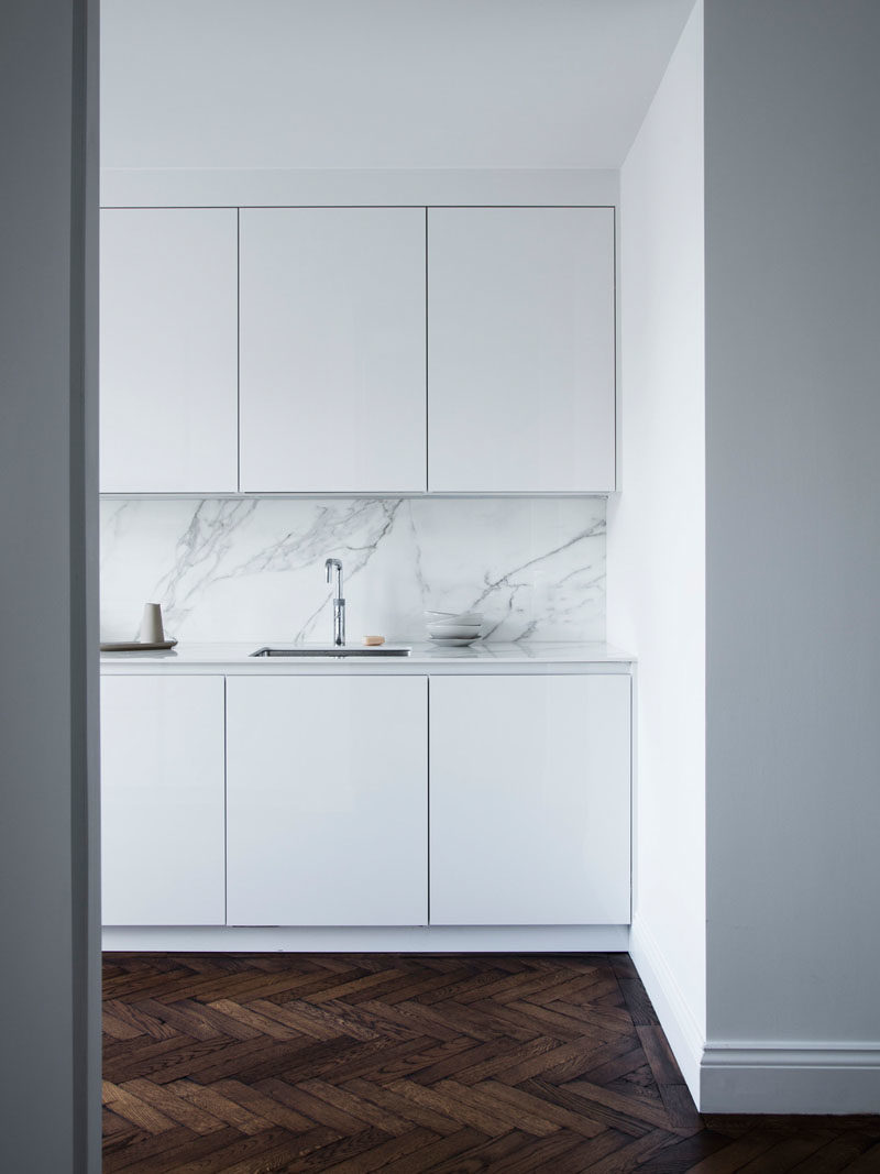 Flooring Ideas - Throughout this renovated house, herringbone oak timber flooring was specified as it would’ve been the original flooring. The designers distressed/damaged the floor and used ‘old English’ stain to give a 200 years old look.  The flooring also contrasts the bright walls and the glossy white minimalist cabinets in the kitchen.#FlooringIdeas #WoodFlooring #DarkFlooring #WhiteKitchen