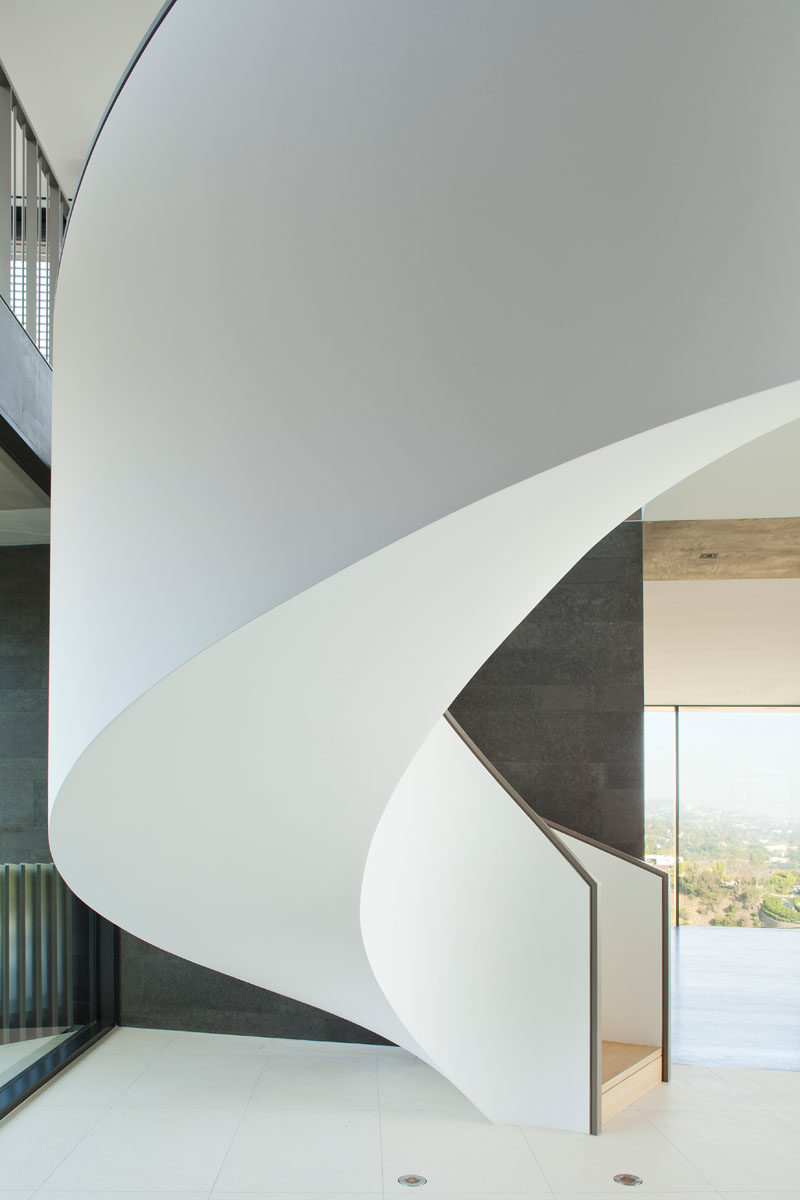 Stair Ideas - This plaster wrapped spiral staircase is a sculptural counterpoint to the bold and linear geometry of the home. #SpiralStairs #SpiralStaircase #StairIdeas #ModernStairs