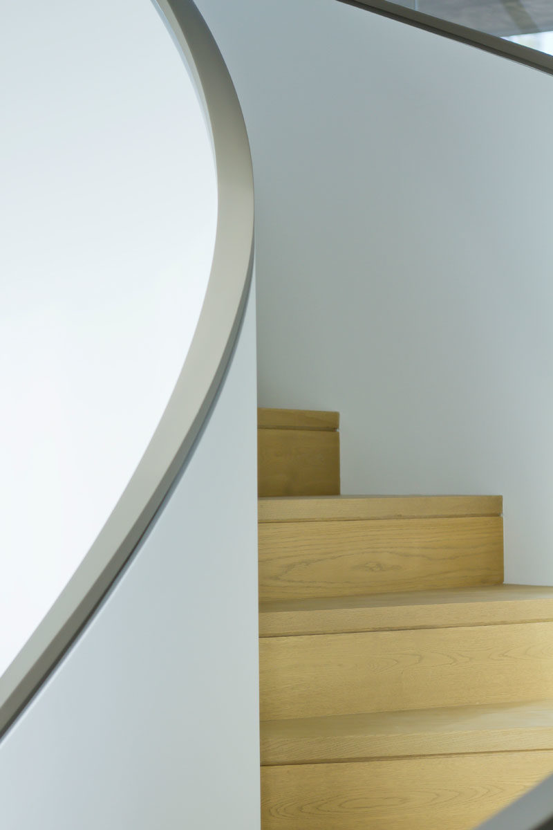 Stair Ideas - This plaster wrapped spiral staircase is a sculptural counterpoint to the bold and linear geometry of the home. #SpiralStairs #SpiralStaircase #StairIdeas #ModernStairs