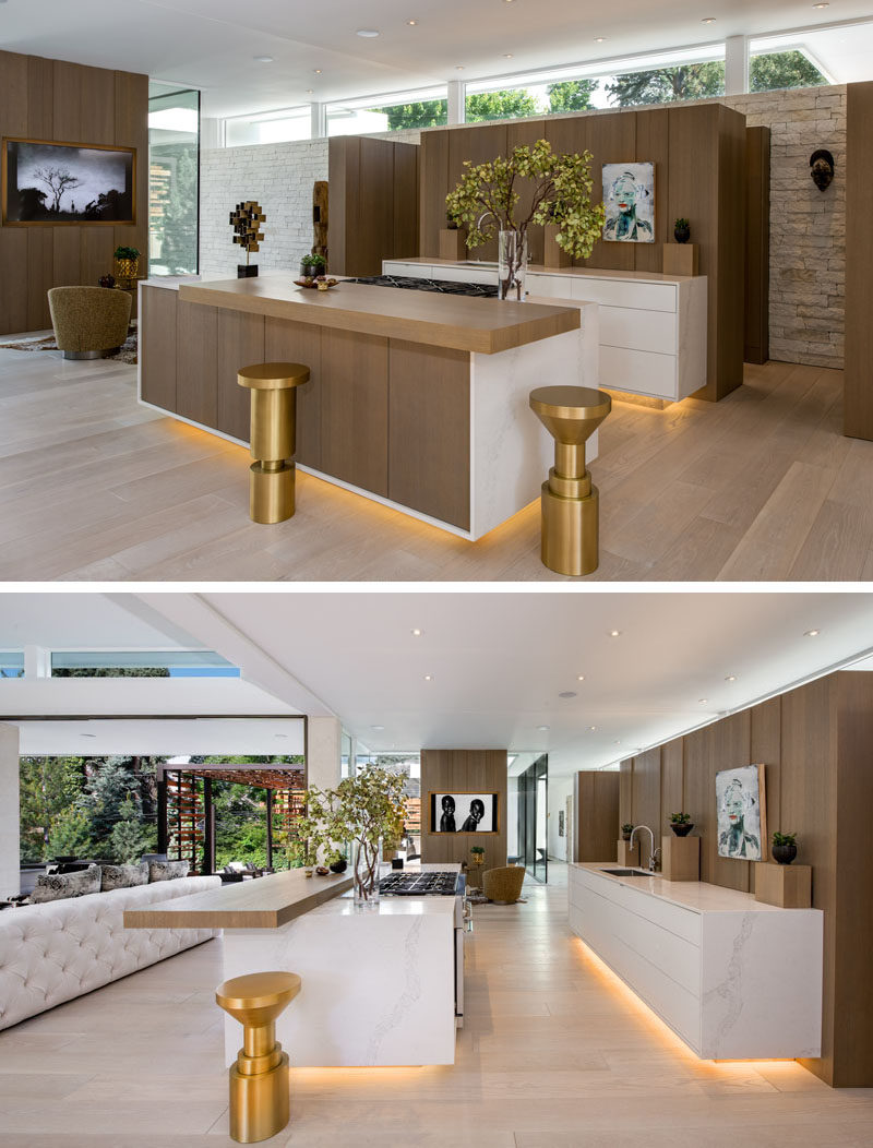 Kitchen Ideas - Clerestory windows are featured throughout this modern house, like in the kitchen. A walk-through pantry is hidden behind the rear kitchen cabinets, while an island provides additional seating space and hidden lighting adds a soft glow. #KitchenIdeas #KitchenDesign #WoodKitchen #Hidden Pantry