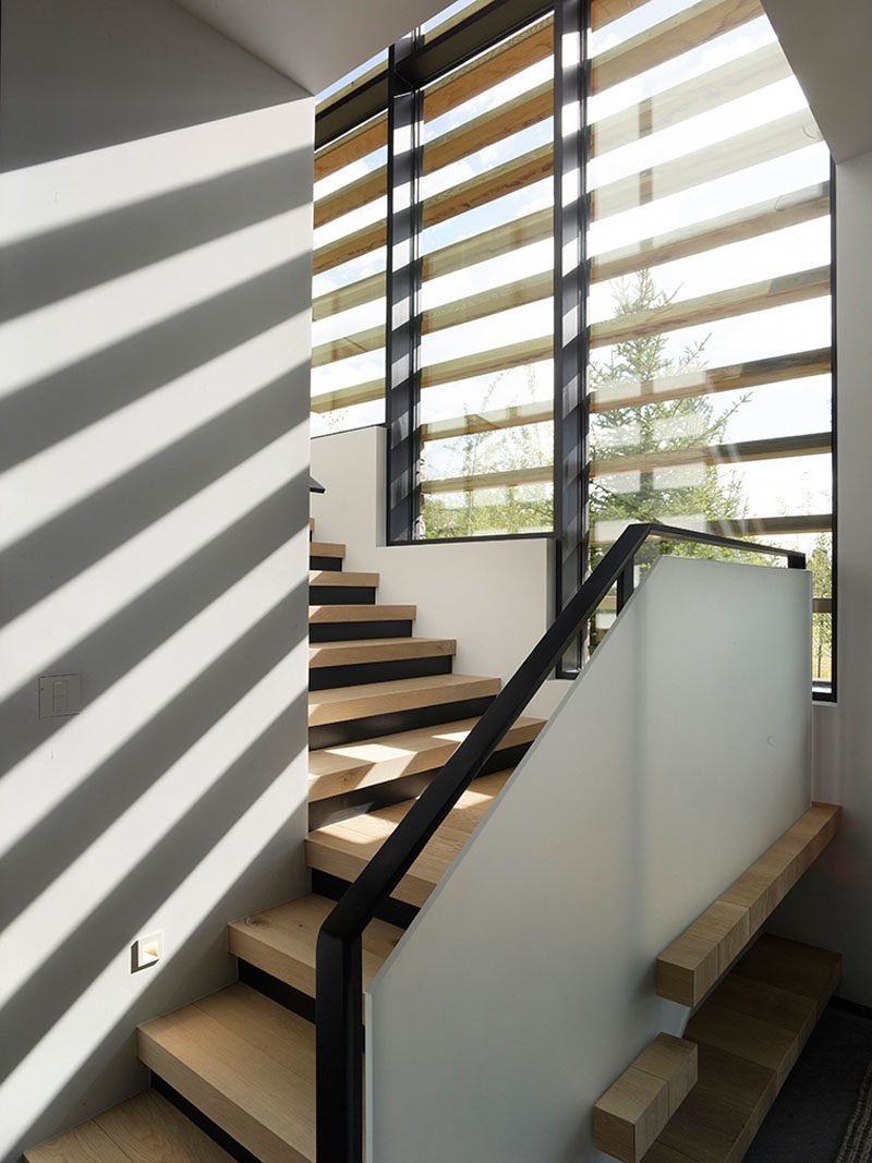 Stair Ideas - These modern wood stairs lead to the upper floor of the home, while the windows have wood accents providing an interesting shadow on the interior walls. #StairIdeas #ModernStairs #StairDesign