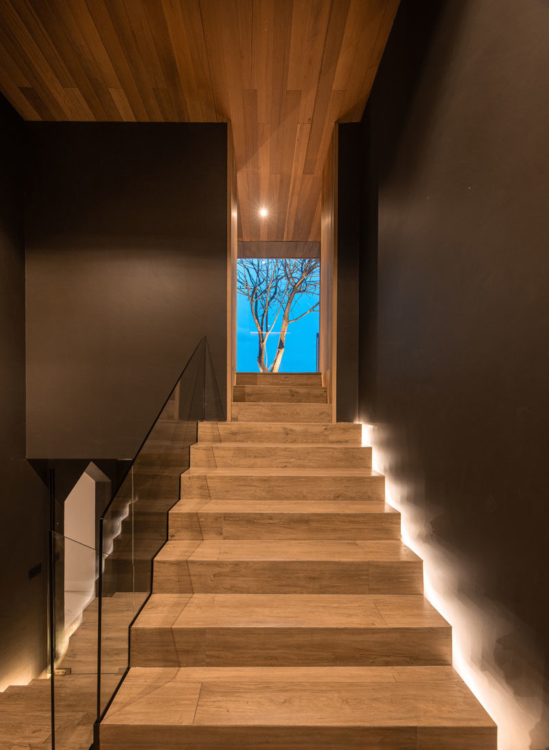 Stair Ideas - This modern rooftop house has wood stairs with hidden lighting and a glass handrail. #StairIdeas #WoodStairs #ModernStairs