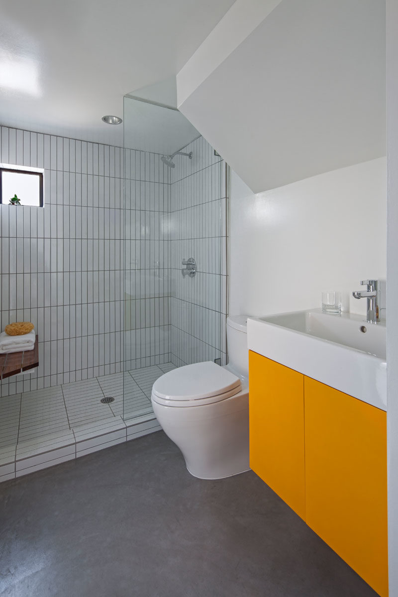 Bathroom Ideas - In this modern bathroom, a walk-in shower has vertically laid tiles, helping to create a sense of height in the small space. #BathroomIdeas #ModernBathroom #BathroomDesign