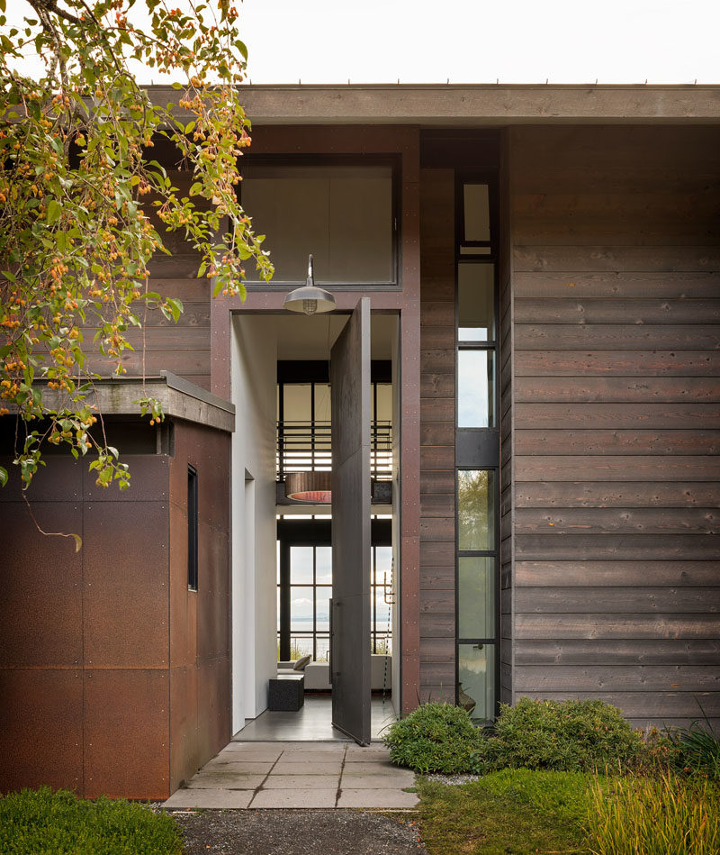 Door Ideas - This modern house features a steel front door that  pivots to reveal a tall hallway that leads to the social areas of the home. #OversizedFrontDoor #FrontDoor #SteelDoor