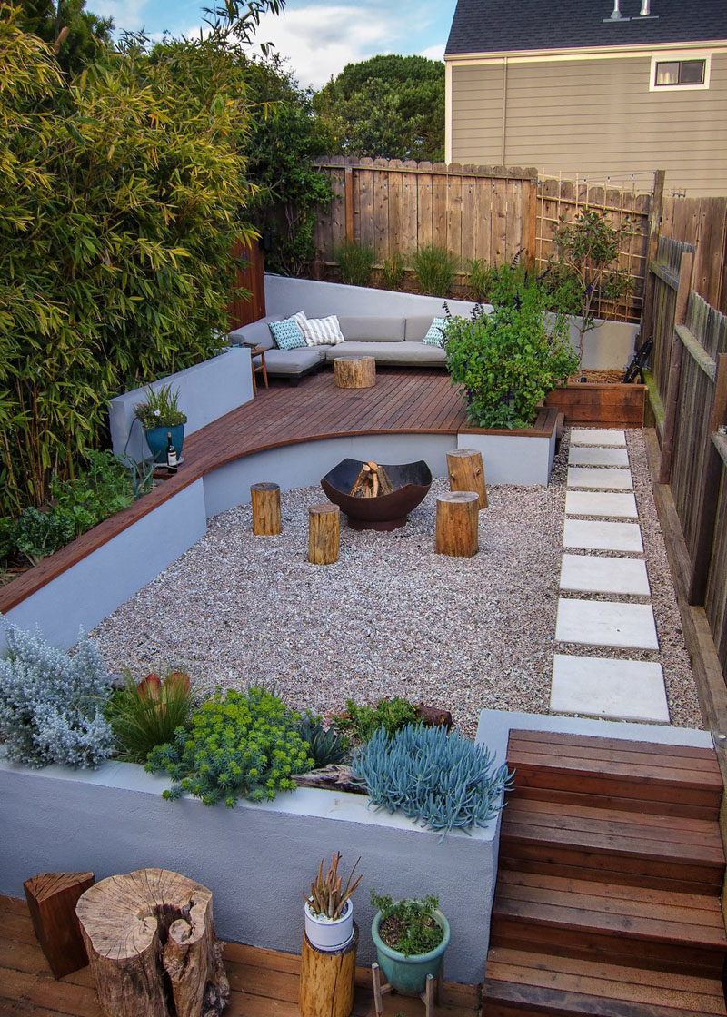 Landscaping Ideas - This modern landscaped backyard has a raised outdoor lounge deck, a wood burning firepit, succulents, bamboo, and a vegetable garden. #LandscapingIdeas #GardenIdeas #PlantIdeas #ModernYard #ModernBackyard #TieredYard