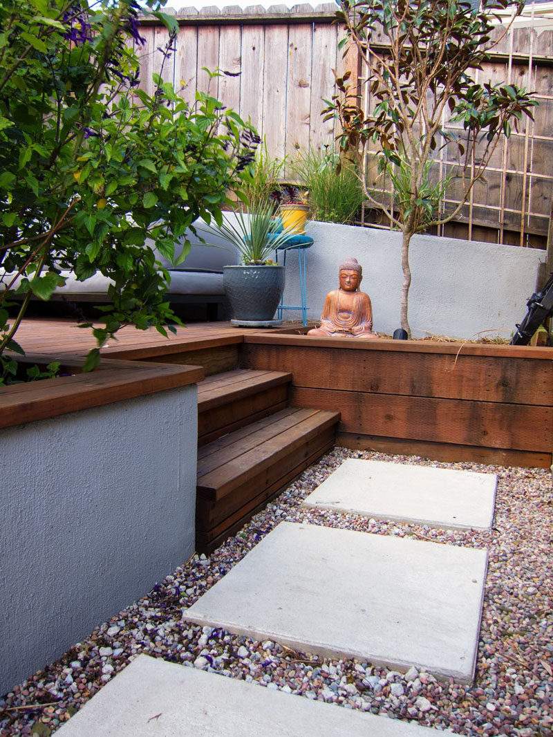 Landscaping Ideas - This modern landscaped backyard has a raised outdoor lounge deck, a wood burning firepit, succulents, bamboo, and a vegetable garden. #LandscapingIdeas #GardenIdeas #PlantIdeas #ModernYard #ModernBackyard #TieredYard