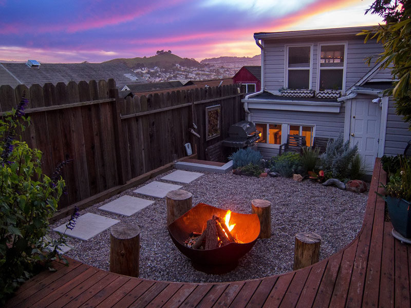 Landscaping Ideas - This modern landscaped backyard has a raised outdoor lounge deck, a wood burning firepit, succulents, bamboo, and a vegetable garden. #LandscapingIdeas #GardenIdeas #PlantIdeas #ModernYard #ModernBackyard #TieredYard