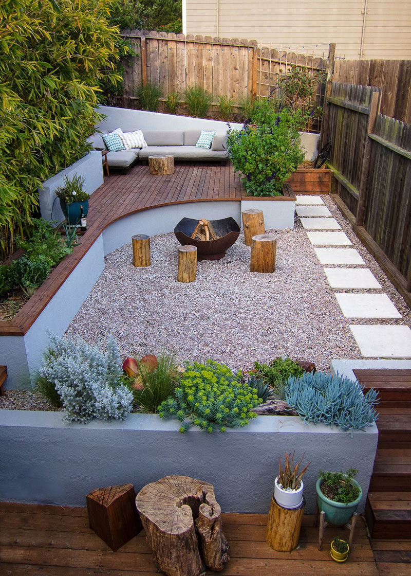 Landscaping Ideas - This modern landscaped backyard has a raised outdoor lounge deck, a wood burning firepit, succulents, bamboo, and a vegetable garden. #LandscapingIdeas #GardenIdeas #PlantIdeas #ModernYard #ModernBackyard #TieredYard