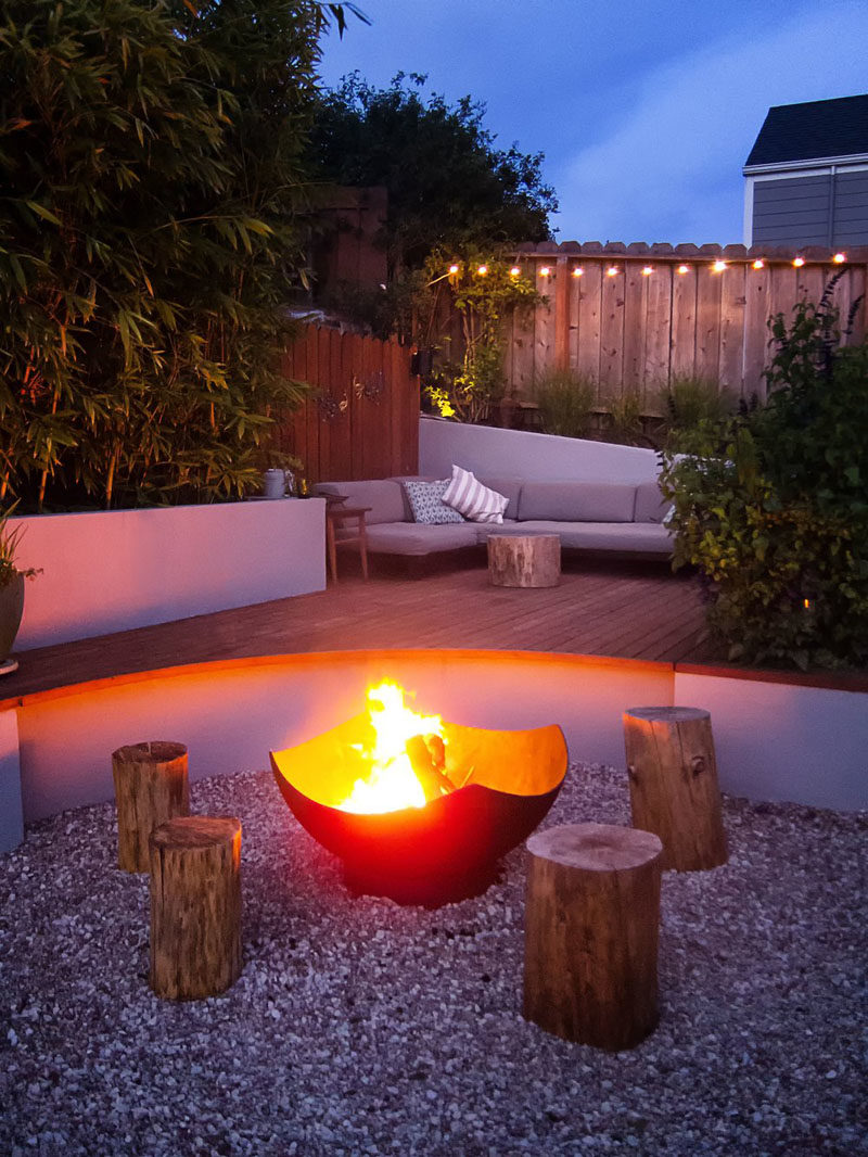 Landscaping Ideas - This modern landscaped backyard has a raised outdoor lounge deck, a wood burning firepit, succulents, bamboo, and a vegetable garden. #LandscapingIdeas #GardenIdeas #PlantIdeas #ModernYard #ModernBackyard #TieredYard