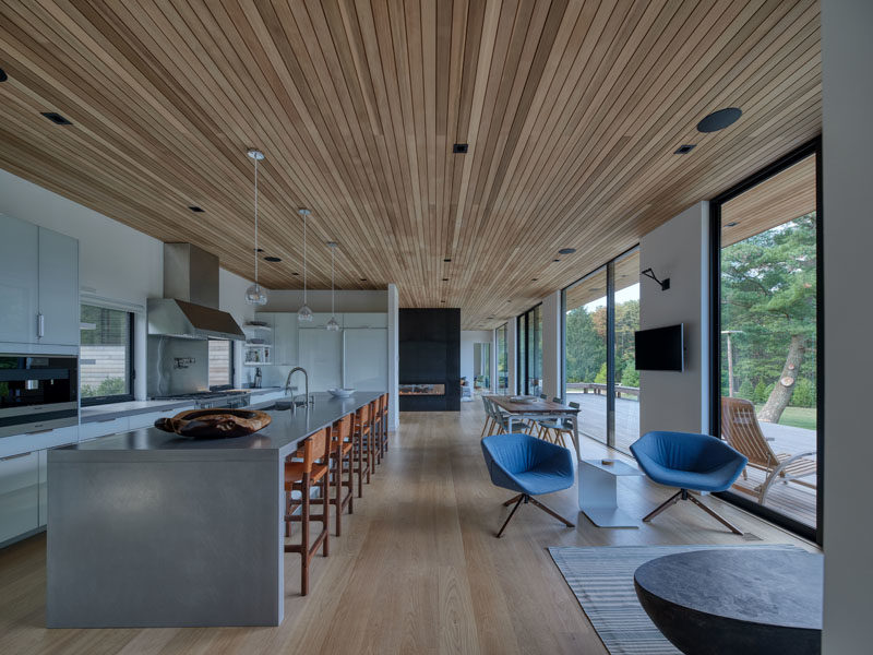 Kitchen Ideas - This modern kitchen has an expansive island that provides ample counter space and room for seating. The wood ceiling travels from the kitchen through to the living room and dining room. #KitchenIdeas #KitchenDesign #ModernKitchen