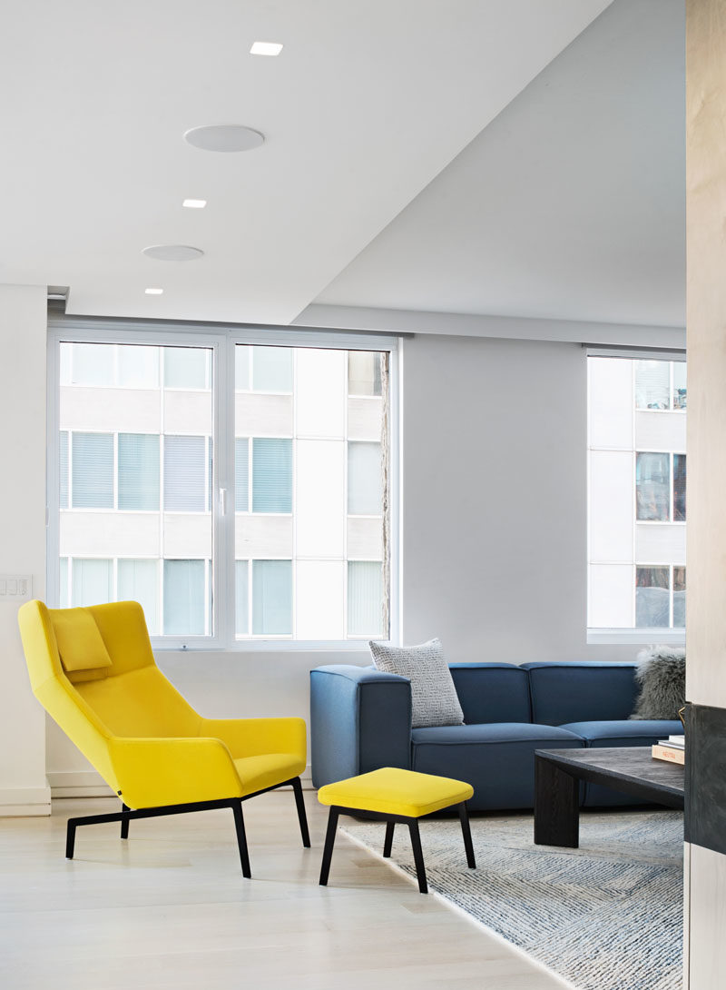 A yellow armchair and ottoman add color, brightness, and a sense of fun to this modern apartment interior. #InteriorDesign #ModernInterior