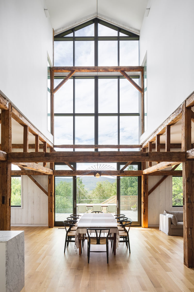 Dining Ideas - Inside this modern barn, the 30 foot ceiling height creates a space that's both open and welcoming, with the old wood elements proudly displayed. Windows flood the dining area with an abundance of natural light. #DiningRroom #Windows #ModernBarn