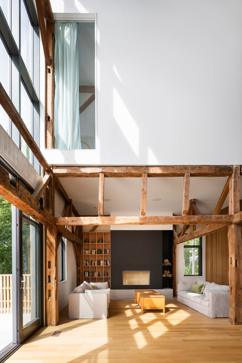 Living Room Ideas - A black fireplace surround provides contrast to the bright interior of the living room, while a custom wood bookshelf adds some storage. #LivingRoom #ModernBarn #LivingRoomIdeas