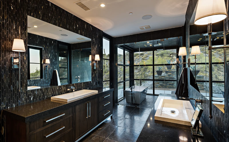 Bathroom Ideas - In this modern bathroom, black tiles create a dramatic appearance, while the freestanding bathtub and dual shower is located within a glass room, making it feel like you're outside. #ModernBathoom #BathroomIdeas #BathroomDesign