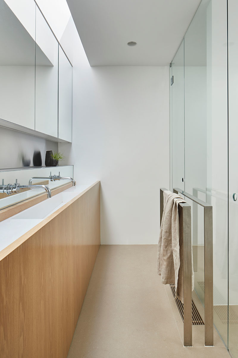 Bathroom Ideas - This modern bathroom showcases a narrow wood-front vanity that runs the length of the wall. #NarrowVanity #ModernBathroom #BathroomIdeas #BathroomDesign