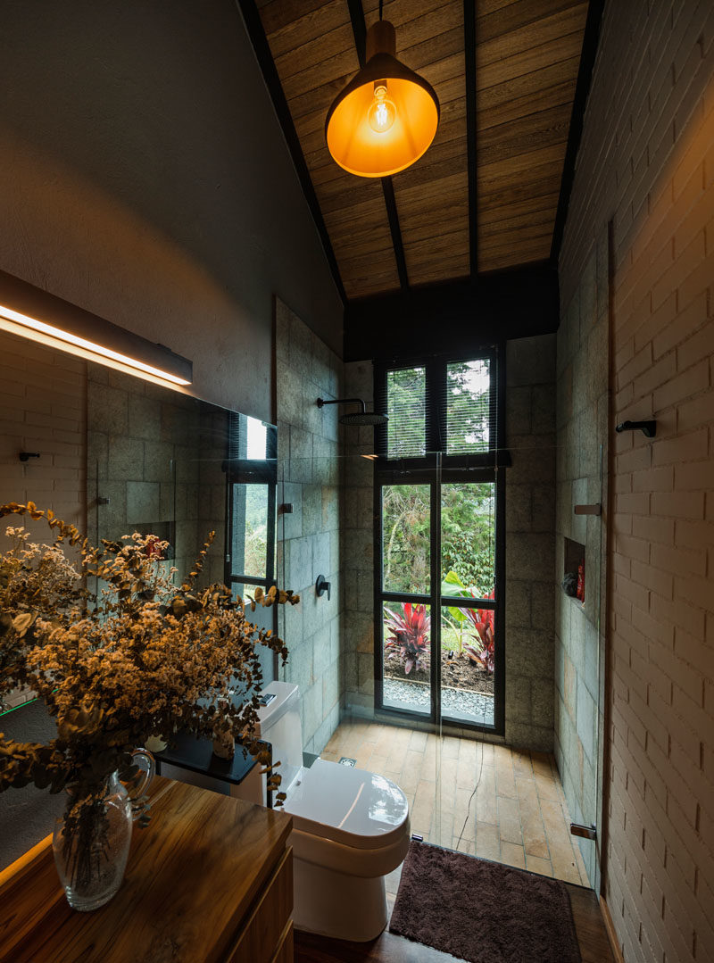 Bathroom Ideas - This modern bathroom features high ceilings, a walk-in shower positioned next to the windows, and a wood vanity. #BathroomIdeas #BathroomDesign